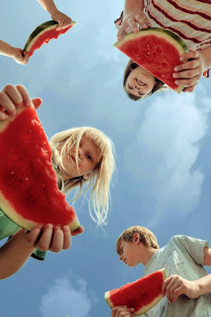 Four children eating watermelon and smiling